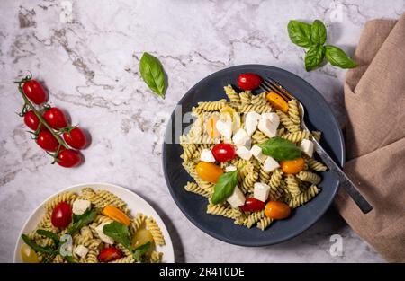 Insalata di pesto fresco con diversi colori di pomodori ciliegini e mozzarella con sfondo chiaro. Foto Stock