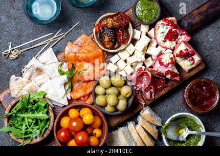 Antipasto. Antipasto con vino. Prosciutto serrano, salmone affumicato, pomodori secchi e freschi formaggio d'oliva, vino a bordo. Vista dall'alto, grigia Foto Stock