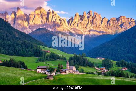 Val di Funes, Dolomiti, Italia. Villaggio di Santa Maddalena di fronte al gruppo montuoso Odle Geisler al tramonto Foto Stock