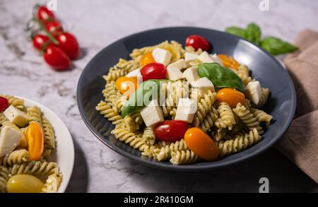 Insalata di pesto fresco con diversi colori di pomodori ciliegini e mozzarella con sfondo chiaro. Foto Stock