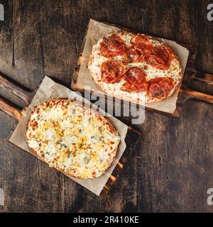 Due pizze romane con formaggio e jamon serrano. Pizza piazza romana o Pinsa su pasta spessa, cucina italiana Foto Stock