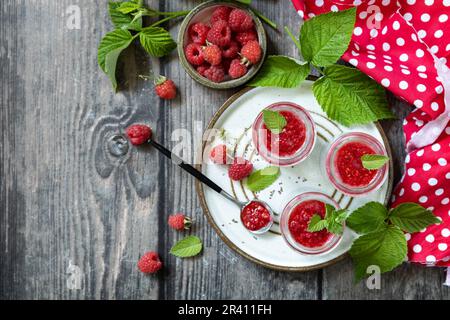 Colazione sana. Vasetti di vetro con budino di chia con lampone e marmellata o frullati con semi di chia su tavola rustica. Vista da un Foto Stock