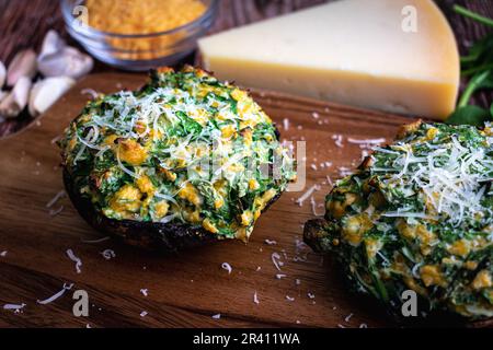 Spinaci e formaggi funghi ripieni sormontati con parmigiano grattugiato: Vista dall'alto di un cappellini di funghi portobello ripieni arrostiti Foto Stock