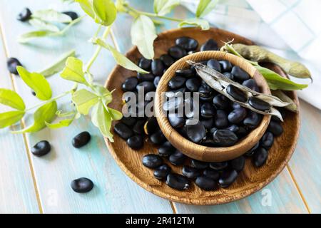 Verdure biologiche crude. Il concetto di vegan o dieta alimentare. Semi di soia neri freschi maturi su un tavolo di legno. Foto Stock