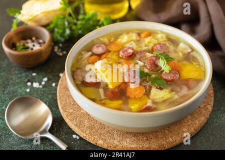 Zuppa tradizionale di cavolo Zelnacka con salsicce e verdure in una ciotola su un tavolo di pietra. Cucina ceca. Foto Stock