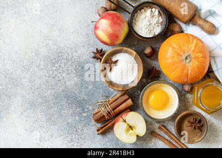 Cottura sfondo cibo. Zucche, mele, miele, noci e spezie di stagione per zucca o torta di mele su un tavolo grigio. Visualizza da Foto Stock