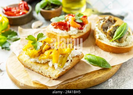 Panini aperti con salmone salato, pomodoro essiccato al sole, melanzane alla griglia, pepe bulgaro alla griglia e formaggio cremoso su una TA di pietra Foto Stock