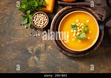 Zuppa vegetariana alla crema di zucca e ceci su un tavolo rustico in legno. Comfort cibo, autunno e inverno sano slow food concetto. Vi Foto Stock