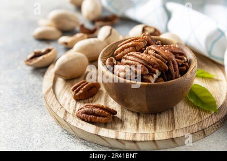 Ciotola con noci pecan su un tavolo di pietra. Noci e semi, grassi sani, vari oligoelementi e vitamine. Spazio di copia. Foto Stock