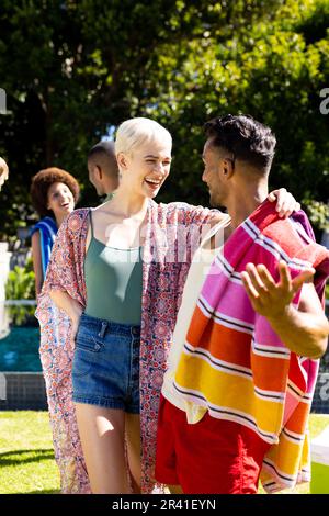 Felice gruppo di amici diversi abbracciando e sorridendo in giardino Foto Stock