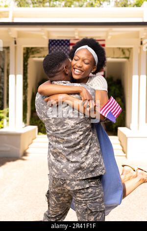 Allegra moglie afro-americana che abbraccia il marito militare dopo il ritorno a casa dall'esercito Foto Stock