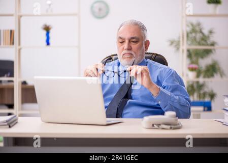 Vecchio dipendente maschile che lavora in ufficio Foto Stock