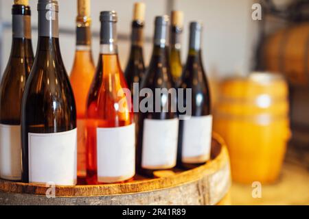 Primo piano di mockup di gruppo di bottiglie di vetro con diversi vini e champagne in barrique di vino in legno Foto Stock