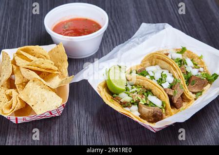 Patatine rosso salsa strada taco pasto 3 tortilla di mais lengua mucca di manzo lingua messicana cuneo di lime Foto Stock