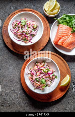 SALMONE CILENO SEVICHE. Salmone crudo fresco marinata con cipolla viola, coriandolo in succo di limone. Ceviche e ingredienti sul grigio Foto Stock