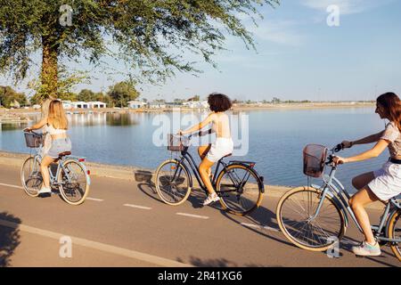 Adolescenti di diverse nazionalità e aspetto in bicicletta percorrono una strada cittadina Foto Stock