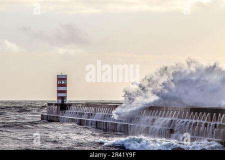 Onde che si infrangono sul vecchio faro. Farolim de Felgueiras, Porto, Portogallo. Foto Stock