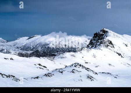 Montagne innevate sotto un cielo blu nuvoloso Foto Stock