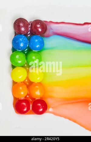 I colori dell'acqua creano un effetto tie dye poiché i colori dell'arcobaleno doppio si perdono su sfondo bianco Foto Stock