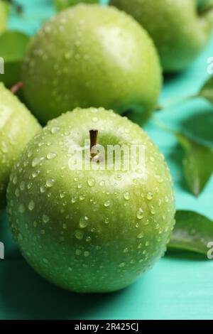 Mele verdi fresche mature con gocce d'acqua su tavola di legno turchese, primo piano Foto Stock