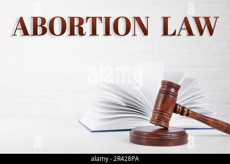 Legge sull'aborto. Gavel e libro sul tavolo su sfondo bianco Foto Stock