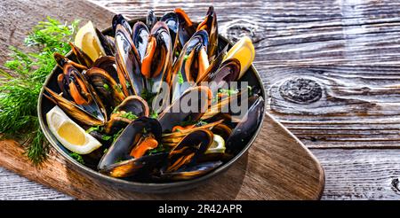 Composizione con un piatto di cozze al vapore servito con prezzemolo e limone Foto Stock