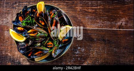 Composizione con un piatto di cozze al vapore servito con prezzemolo e limone Foto Stock