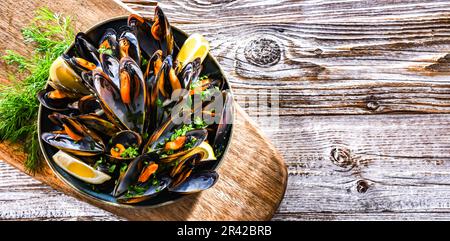 Composizione con un piatto di cozze al vapore servito con prezzemolo e limone Foto Stock