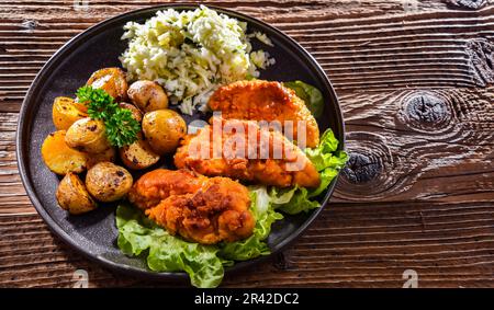 Cotolette di pollo impanate servite con patate e cavolo. Foto Stock