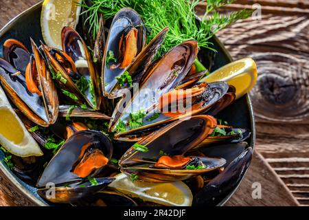 Composizione con un piatto di cozze al vapore servito con prezzemolo e limone Foto Stock