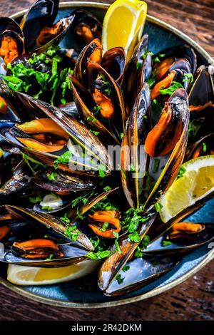 Composizione con un piatto di cozze al vapore servito con prezzemolo e limone Foto Stock