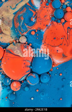 Grandi palline circolari di arancio blu e oro in stract pour di olio di pittura acrilica e esperimento latte creando asset di fondo Foto Stock