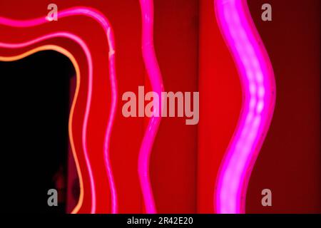 Luci al neon rosa che conducono a una porta scura Foto Stock