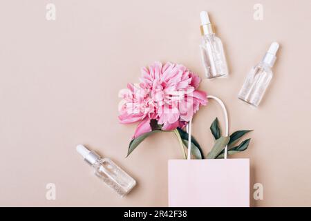 Prodotti cosmetici in gel liquido e peonia rosa in sacchetto di carta. Concetto di cura della pelle di bellezza Foto Stock