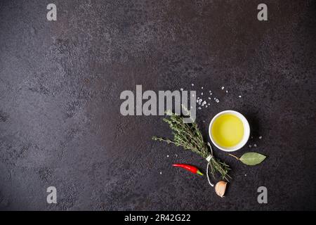 Olio d'oliva e bouquet di timo su fondo di pietra nera Foto Stock