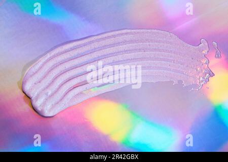 Sampl di gel prodotto di bellezza su sfondo olografico. Swatch in gel cosmetico trasparente con riflessi iridescenti Foto Stock