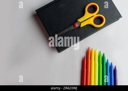 Design piatto della scrivania da ufficio con cancelleria colorata e strumenti di scrittura come penne da schizzo, forbici e un libro, su uno sfondo bianco Foto Stock