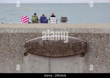 Targa di legno con incisa la vista di Cushing, attaccata al muro di mare di Whitstable Beach, in onore del famoso attore Peter Cushing che vi sedeva spesso. Foto Stock