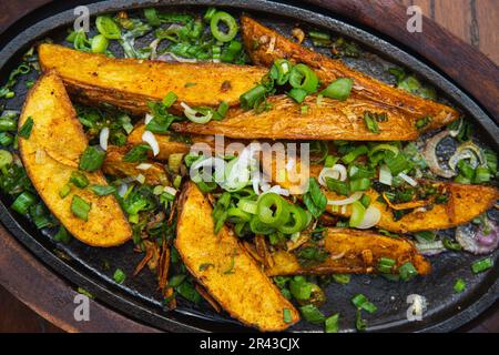 Un piatto di spicchi di patate fritte con erbe speziate Foto Stock