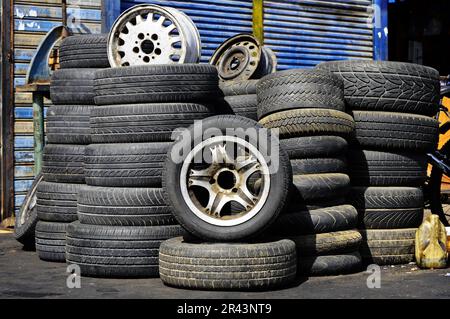 Pile di vecchi pneumatici usati nella parte anteriore dell'auto alla stazione di servizio Foto Stock