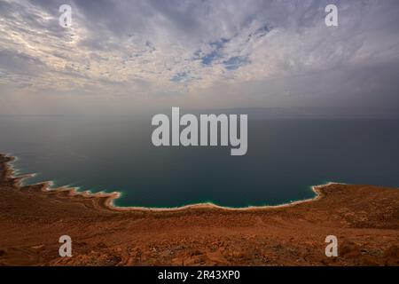 Mar Morto, paesaggio dalla vista della Giordania. Costa, acqua con cielo blu con nuvole. Lago salato confinante con la Giordania a est e la Cisgiordania e Israele t Foto Stock