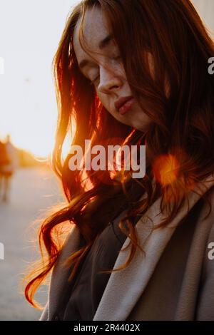 Ginger Girl con Freckles al tramonto vicino a Old Architecture Foto Stock