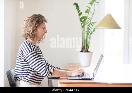 giovane donna che digita in ufficio con un computer portatile Foto Stock