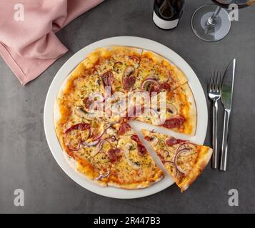 Pizza con pancetta e funghi su piatto di porcellana su tavolo di pietra Foto Stock