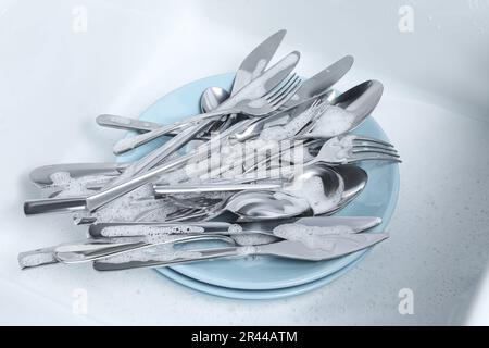 Lavaggio cucchiai, forchette e coltelli in schiuma d'argento Foto Stock