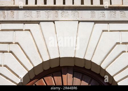 Primo piano di un arco medievale in marmo bianco con serratura e porta in legno marrone, cornice completa, fotografia. Brescia centro, Lombardia, Italia, Europa. Foto Stock