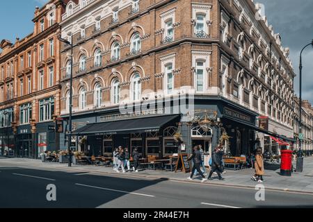 Londra, Regno Unito - 13 aprile 2023: Persone che camminano su una strada di fronte al Jack Horner, un tradizionale pub vittoriano con pannelli di quercia su Tottenham Court Road. Foto Stock