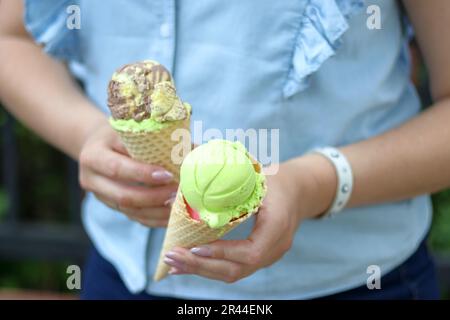 Una donna tiene un cono gelato in entrambe le mani. Primo piano. Foto Stock