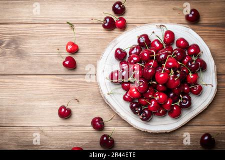 Set di ciliegie rosse ricche e sane su una base di legno. Frutti ricchi di vitamine per una dieta sana Foto Stock
