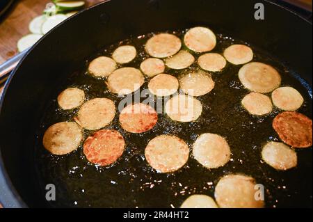 Friggere o rosolare le fette di zucchine o zucchine in olio di girasole pronte per l'uso in un piatto di pasta italiana Foto Stock